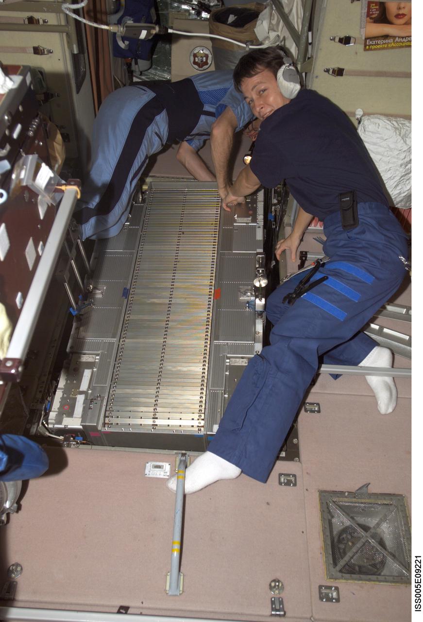 ISS005-E-09221 (7 August 2002) --- Cosmonaut Sergei Y. Treschev (left) and astronaut Peggy A. Whitson, both Expedition Five flight engineers, perform maintenance on the Treadmill Vibration Isolation System (TVIS) in the Zvezda Service Module on the International Space Station (ISS). Treschev represents Rosaviakosmos.