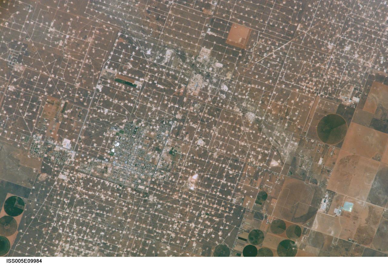 ISS005-E-9984 (17 August 2002) --- This digital still photograph, taken from the International Space Station (ISS)   during its fifth staffing, depicts both agriculture and the petroleum industry, which compete for land use near Denver City, Texas. The photo was recently released by the  Earth Sciences and Image Analysis Laboratory at Johnson Space Center. The area is southwest of Lubbock near the New Mexico border.  According to analysts studying the station imagery, the economy of this region is almost completely dependent on its underground resources of petroleum and water.  Both resources result in distinctive land use patterns visible from space.  Historically this area has produced vast quantities of oil and gas since development began in the 1930s.  A fine, light-colored grid of roads and pipelines connect well sites over this portion of the Wasson Oil Field, one of the state&#0146;s most productive.  Since the 1940s, agricultural land use has shifted from grazing to irrigated cultivation of cotton, sorghum, wheat, hay, and corn.  The water supply is drawn from wells tapping the vast Ogallala Aquifer.  Note the large, circular center-pivot irrigation systems in the lower corners of the image.  The largest is nearly a mile in diameter.