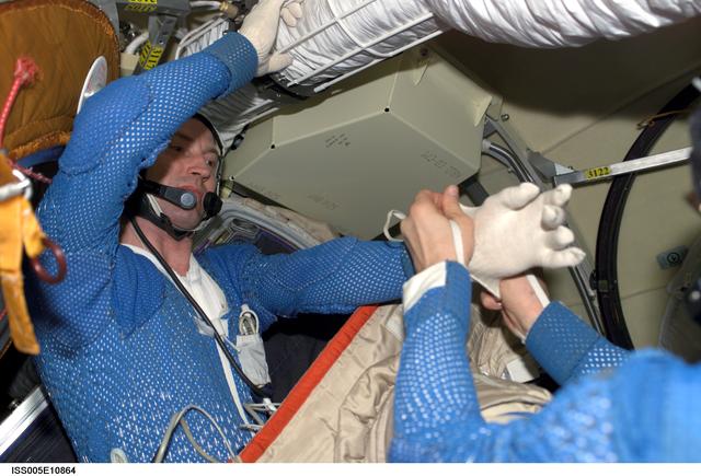 NASA image: Korzun helps Treschev with his LCVG in the Pirs Docking Compartment during Expedition Five