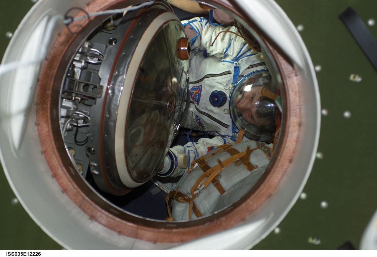 ISS005-E-12226 (3 September 2002) --- Cosmonaut Sergei Y. Treschev, Expedition Five flight engineer, wearing a Russian Sokol suit, moves through a hatch in a Soyuz spacecraft that is docked to the International Space Station (ISS). Treschev represents Rosaviakosmos.