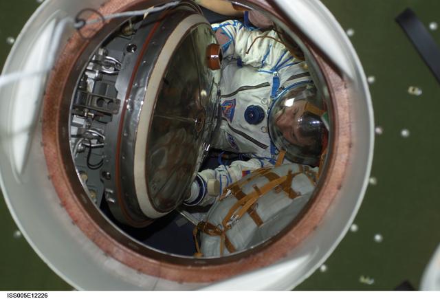 NASA image: Treschev wearing a Russian Sokol suit moves through hatch in the Soyuz spacecraft