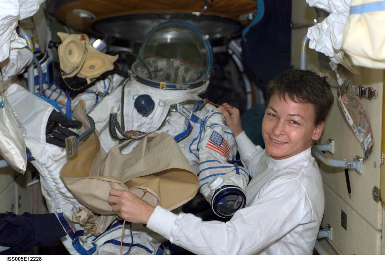 ISS005-E-12228 (3 September 2002) --- Astronaut Peggy A. Whitson, Expedition Five flight engineer, is pictured holding a Russian Sokol suit in the functional cargo block (FGB), or Zarya on the International Space Station (ISS).