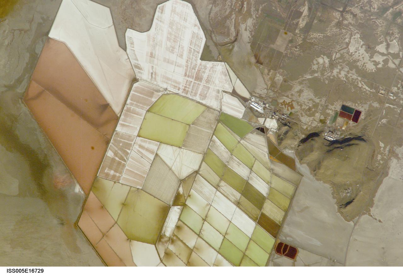 ISS005-E-16729 (7 October 2002) --- Great Salt Lake, Utah, is featured in this image photographed by an Expedition 5 crewmember on the International Space Station (ISS). Great Salt Lake serves as a striking visual marker for crewmembers orbiting over North America. A sharp line across its center is caused by the restriction in water flow from the railroad causeway. The eye-catching colors of the lake stem from the fact that Great Salt Lake is hyper saline, typically 3-5 times saltier than the ocean, and the high salinities support sets of plants and animals that affect the light-absorbing qualities of the water. North of the causeway salinities are higher, and the water turns red from the pigments of halophilic bacteria. In the shallower corner of the lake, earthen dikes mark large salt evaporation works, which take on the jewel tones of turquoise, russet, tamber and pearl white.