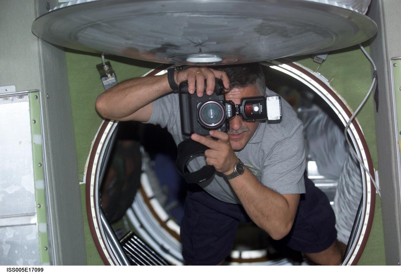 ISS005-E-17099 (10 October 2002) --- Cosmonaut Fyodor N. Yurchikhin, STS-112 mission specialist, uses a still photo camera while floating into the Zvezda Service Module on the International Space Station (ISS). Yurchikhin represents Rosaviakosmos.