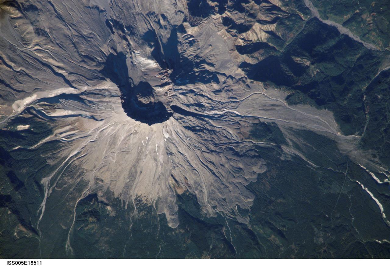 ISS005-E-18511 (25 October 2002) --- Mount Saint Helens, Washington, is featured in this image photographed by an Expedition 5 crewmember on the International Space Station (ISS). On May 18, 1980, Mount Saint Helens volcano erupted. A series of earthquakes preceded the eruption, triggering a collapse of the north side of the mountain into a massive landslide. This avalanche coincided with a huge explosion that destroyed over 270 square miles of forest in a few seconds, and sent a billowing cloud of ash and smoke 80,000 feet into the atmosphere. The crewmembers on the Station captured this detailed image of the volcano’s summit caldera. In the center of the crater sits a lava dome that is 876 feet above the crater floor and is about 3,500 feet in diameter. The upper slopes of the 1980 blast zone begin at the gray colored region that extends north (upper left) from the summit of the volcano. The deeply incised valley to the left (west) is the uppermost reach of the South Fork of the Toutle River. Devastating mudslides buried the original Toutle River Valley to an average depth of 150 feet, but in places up to 600 feet. The dark green area south of the blast zone is the thickly forested region of the Gifford Pinchot National Forest.
