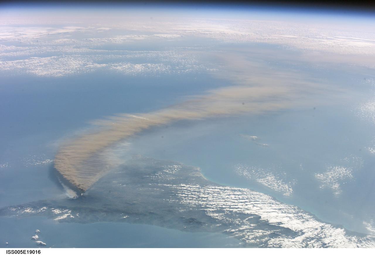 ISS005-E-19016 (30 October 2002) --- The three-member crew of the Expedition Five mission onboard the International Space Station was able to observe Mt. Etna’s spectacular eruption, and photograph the details of the eruption plume and smoke from fires triggered by the lava as it flowed down the 11,000 ft mountain. This image and a second image (ISS005-E-19024) are looking obliquely to the southeast over the island of Sicily. This wide view shows the ash plume curving out toward the horizon, caught first by low-level winds blowing to the southeast, and to the south toward Africa at higher altitudes. Ashfall was reported in Libya, more than 350 miles away. The lighter-colored plumes downslope and north of the summit (see detailed view taken the same day, ISS005-E-19024) are produced by forest fires set by lava flowing into the pine forests on the slope of the mountain. The detailed image provides a more three-dimensional profile of the eruption plume. This eruption was one of Etna’s most vigorous in years, volcanologists reported this week. The eruption was triggered by a series of earthquakes on October 27, 2002, they said. These images were taken on October 30. Although schools were closed and air traffic was diverted because of the ash, no towns or villages were reported to have been threatened by the lava flow.