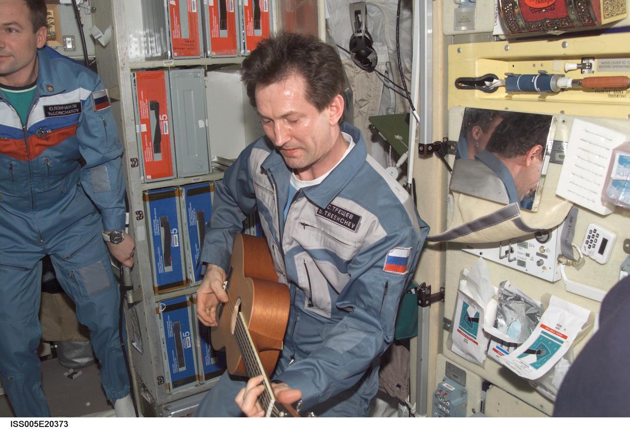 ISS005-E-20373 (8 November 2002) --- Cosmonaut Sergei Y. Treschev, Expedition Five flight engineer, plays host to some “visitors” to the International Space Station (ISS) as he performs on a guitar in the Zvezda Service Module on the International Space Station (ISS). Soyuz 5 Commander Sergei Zalyotin is partially out of frame to the left of Treschev. Zalyotin and Treschev represent Rosaviakosmos.