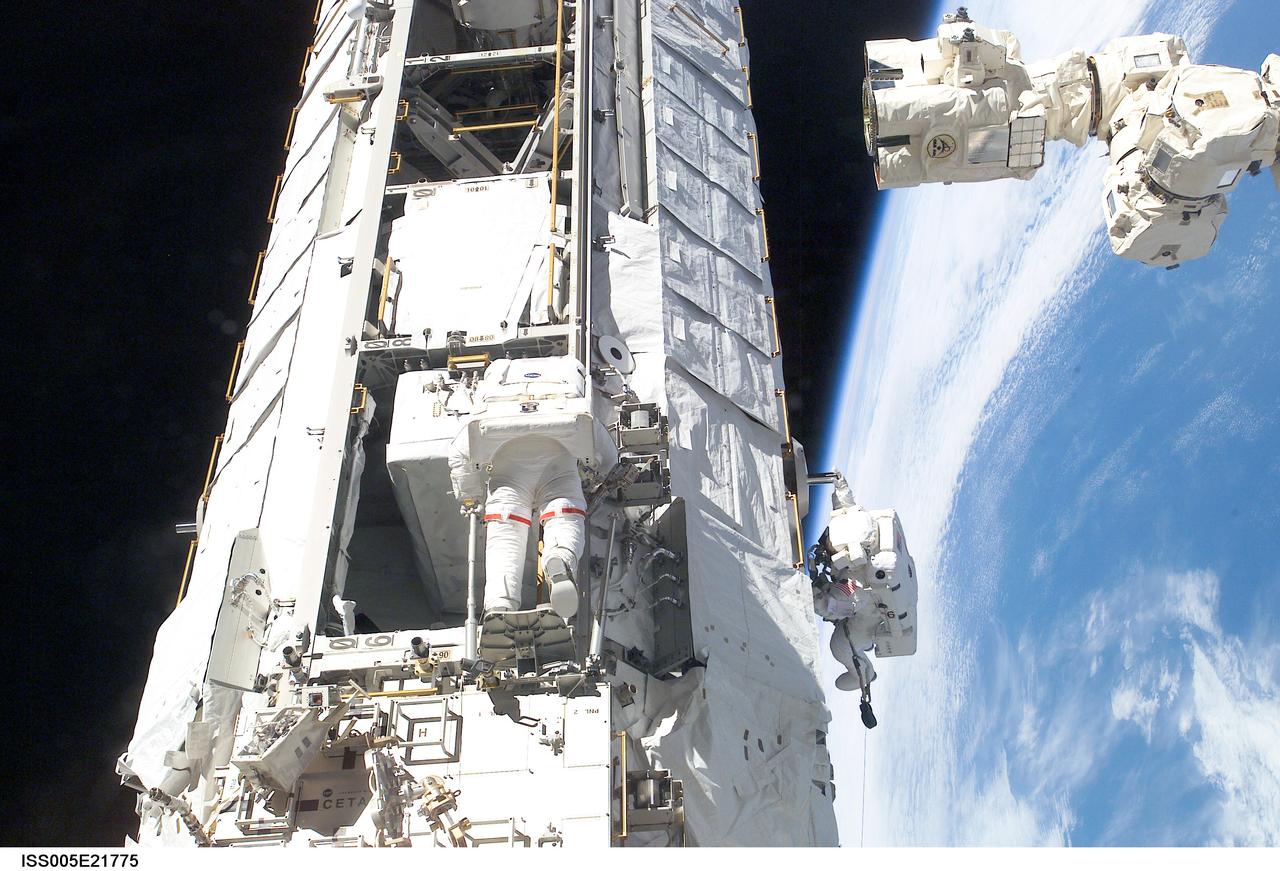 ISS005-E-21775 (28 November 2002) --- Astronauts Michael E. Lopez-Alegria (left) and John B. Herrington, STS-113 mission specialists, work on the newly installed Port One (P1) truss on the International Space Station (ISS) during a session of extravehicular activity (EVA). The end effector of the Canadarm2 / Space Station Remote Manipulator System (SSRMS) and Earth’s horizon are visible in right frame.