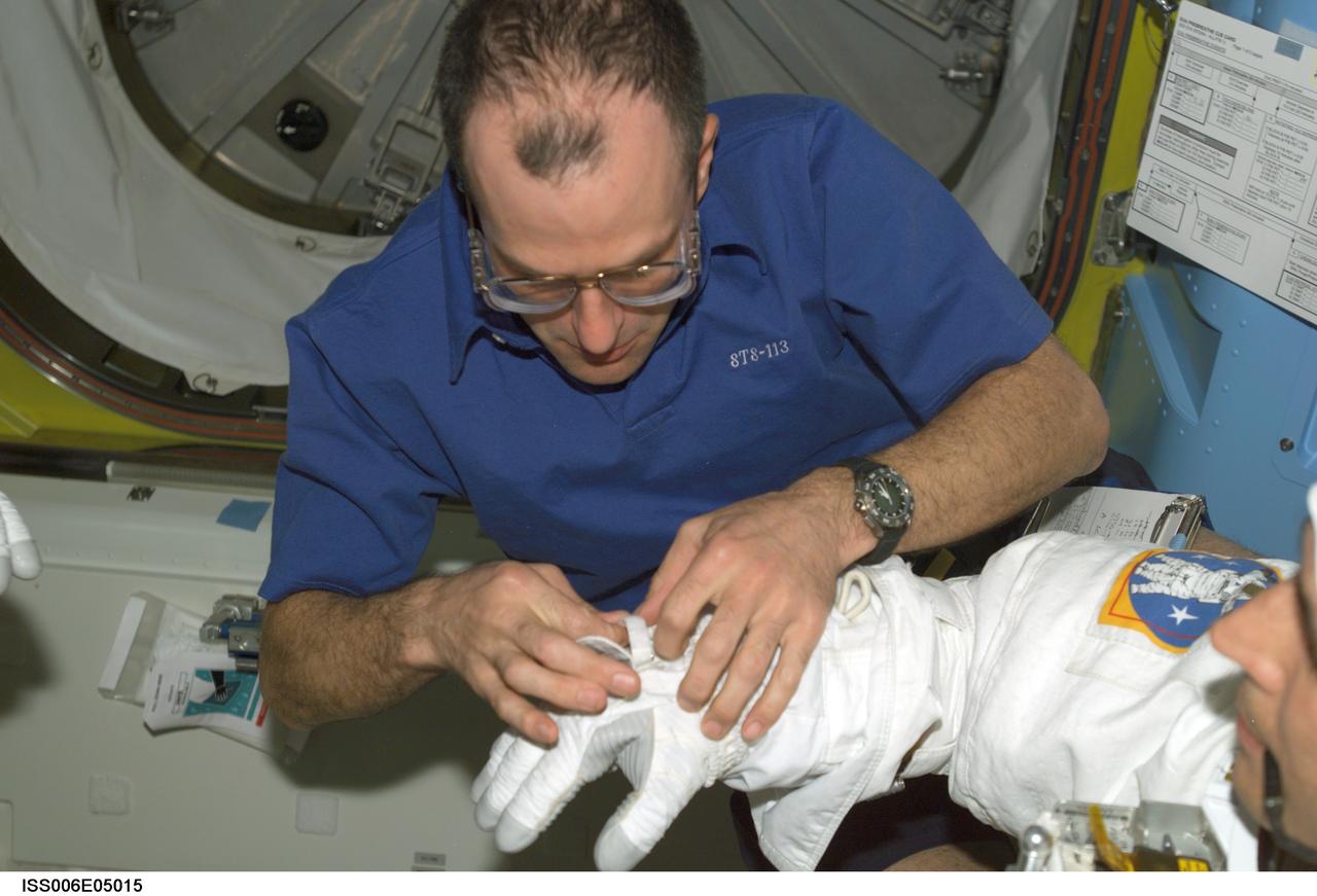 ISS006-E-05015 (28 November 2002) --- Astronaut Donald R. Pettit, NASA ISS science officer, assists astronaut John B. Herrington (partially out of frame), STS-113 mission specialist, with his Extravehicular Mobility Unit (EMU) spacesuit in the Quest Airlock on the International Space Station (ISS).