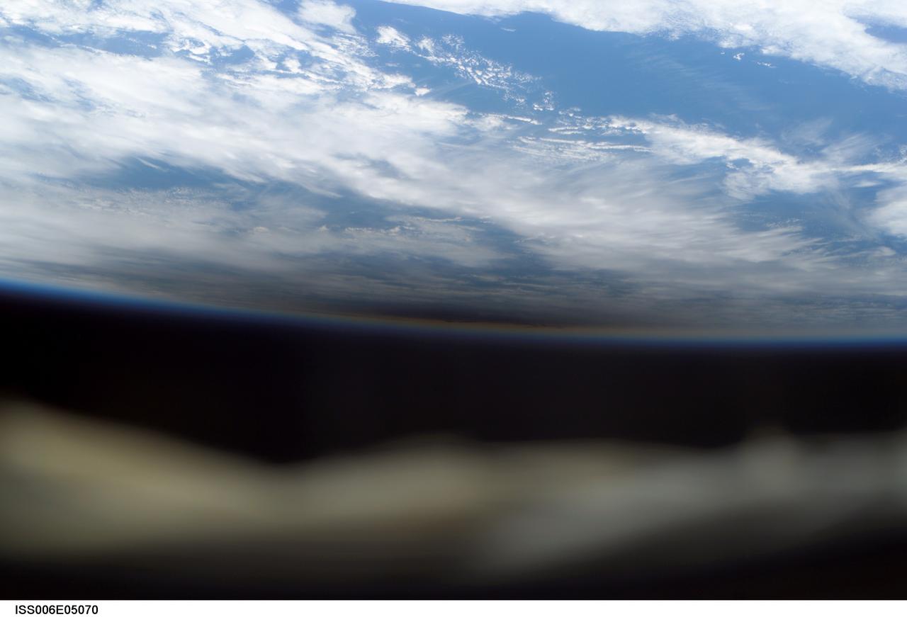 ISS006-E-05070 (4 December 2002) --- The new crewmembers aboard the International Space Station (ISS) were able to document a rare occurrence early into their tour on the outpost. The dark area near Earth's horizon at center frame is actually a shadow cast by the Moon during the total solar eclipse of Dec. 4, 2002. The shadow obscures an area of cloud cover. The station, with three Expedition Six crewmembers aboard, was over the Indian Ocean at the time of the eclipse. The out-of-focus object in the foreground is part of the frame for the viewing port.