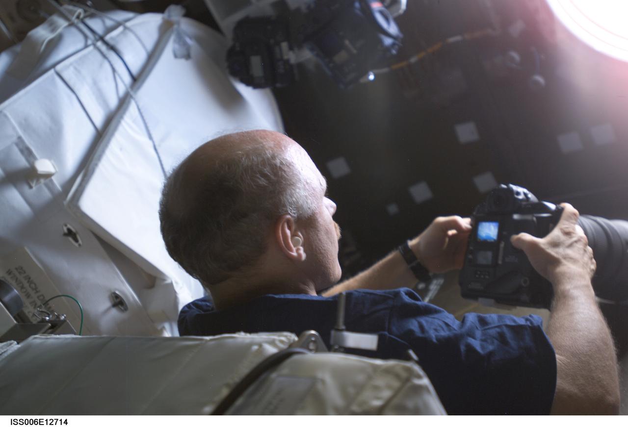 ISS006-E-12714 (27 December 2002) --- Astronaut Kenneth D. Bowersox, Expedition Six mission commander, holds a still camera as he studies the topography of a point on Earth from the nadir window in the Destiny laboratory on the International Space Station (ISS).