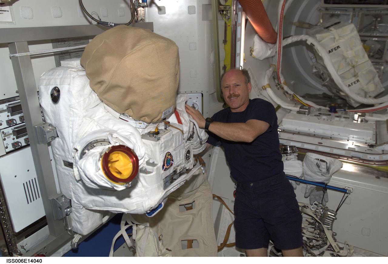 ISS006-E-14040 (4 January 2003) --- Astronaut Kenneth D. Bowersox, Expedition Six mission commander, is pictured near the torso portion of an Extravehicular Mobility Unit (EMU) spacesuit stored in the Quest Airlock on the International Space Station (ISS). Bowersox and Donald R. Pettit, NASA ISS science officer, are scheduled for the mission&#0146;s only spacewalk on January 15, 2003 where they will continue outfitting the station&#0146;s Port One (P1) truss.