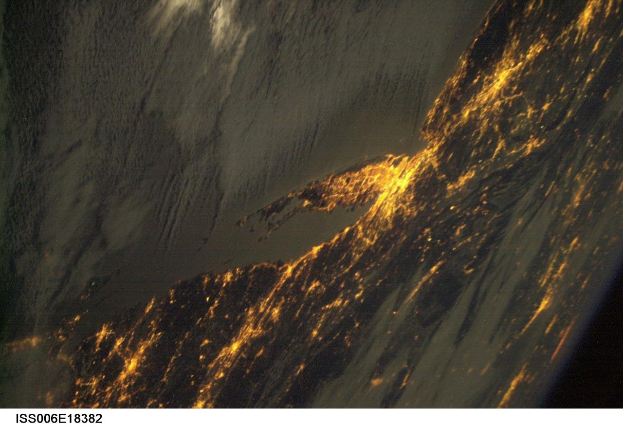 ISS006-E-18382 (January 2003) --- Bright city lights along the coastline and interior of the eastern coast of the United States were captured with a digital still camera by one of the Expedition Six crewmembers on board the International Space Station (ISS). This nighttime view shows New York City, the largest and brightest metropolitan area along the coast. The metropolitan area straddles the Hudson River and spreads eastward over western Long Island. The second largest city in this image is Philadelphia. The crew of the station took this image from a vantage point well to the northwest with the camera pointed back towards New York City and the coast. The result is that the perspective is highly distorted but still recognizable. Low clouds have formed over the waters of the Atlantic and have settled into some of the valleys of the Appalachian Mountains to the northwest.