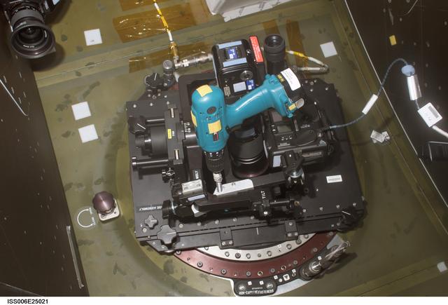 NASA image: View of a "Barn Door Tracker" that is mounted on a camera and attached to the window in the U.S. Lab