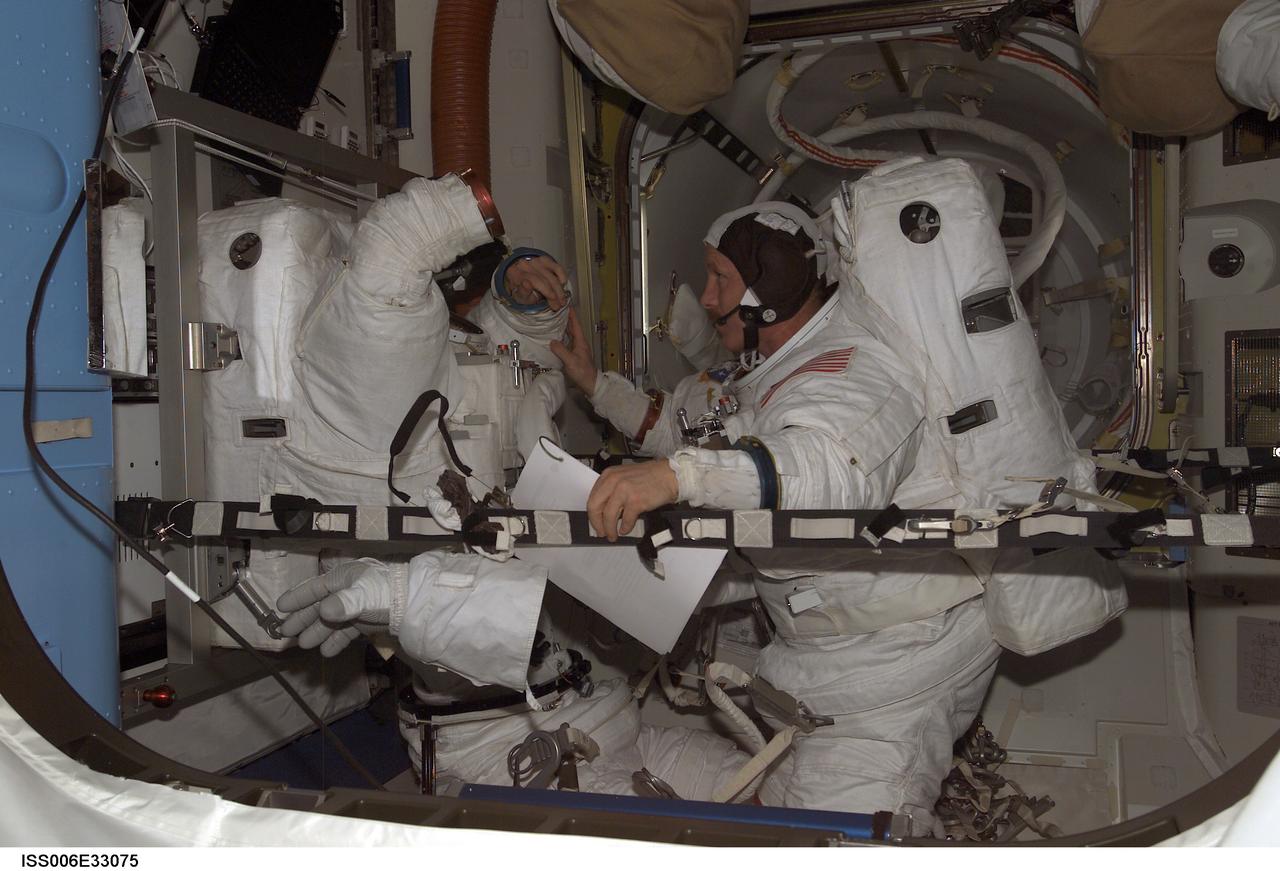 ISS006-E-33075 (24 February 2003) --- Astronauts Kenneth D. Bowersox (right) and Donald R. Pettit, Expedition Six mission commander and NASA ISS science officer, respectively, participate in a scheduled extravehicular activity (EVA) development test objective (DTO) in the Quest Airlock on the International Space Station (ISS). The test demonstrated the ability of two crewmembers to safely get into the American Extravehicular Mobility Unit (EMU) spacesuit without the assistance of a third crewmember; that ability is a prerequisite to sending smaller crews to ISS while the space shuttle fleet remains grounded during the investigation of the Columbia accident. Bowersox and Pettit helped each other into their EMU spacesuits, donned jet backpacks called Simplified Aid for EVA Rescue (SAFER), set up the necessary equipment for a pre-breathe of oxygen to purge nitrogen from their bloodstreams, and then got out of the spacesuits.