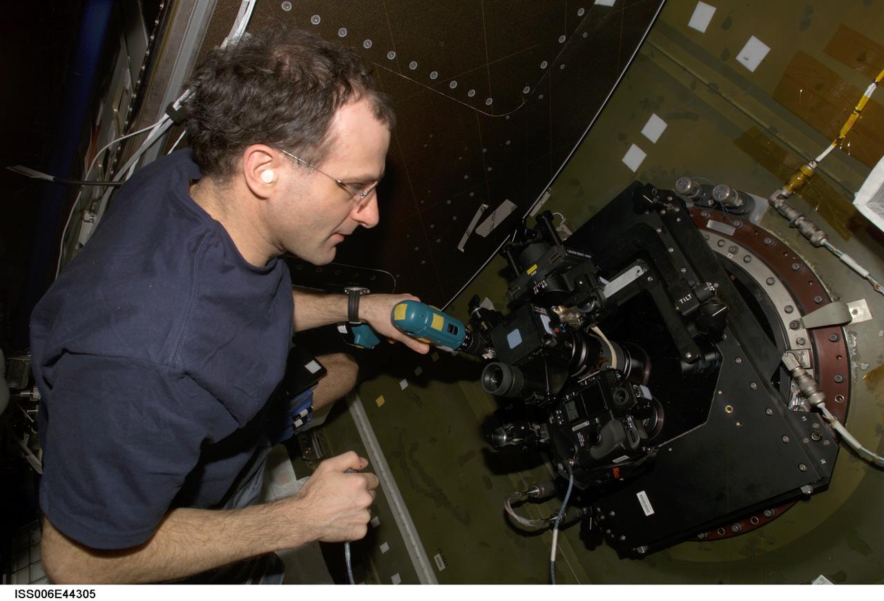 ISS006-E-44305 (5 April 2003) --- Astronaut Donald R. Pettit, Expedition Six NASA ISS science officer, runs a drill while looking through a camera mounted on the nadir window in the Destiny laboratory on the International Space Station (ISS). The device is called a &#0147;barn door tracker&#0148;. The drill turns the screw, which moves the camera and its spotting scope.