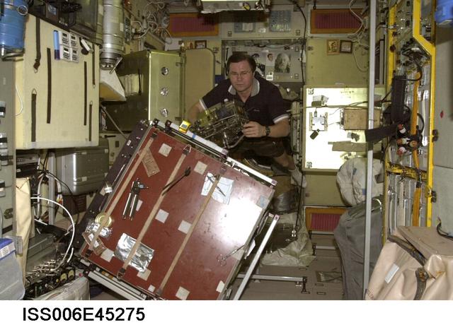 ISS006-E-45275 (21 March 2003) --- Cosmonaut Nikolai M. Budarin, Expedition Six flight engineer, holds a piece of hardware near a worktable in the Zvezda Service Module on the International Space Station (ISS). Budarin represents Rosaviakosmos.