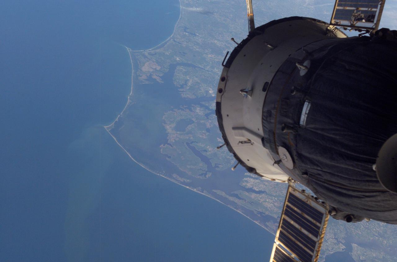 ISS006-E-50419 (2003) --- This digital still camera image of Cape Hatteras and Cape Lookout, North Carolina, with a Soyuz vehicle docked to the orbital outpost in the foreground was taken by Expedition 6 crewmember Don Pettit during his 5 1/2 month stay on the International Space Station (ISS).  The largest inland body of water is Pamlico Sound.  Kitty Hawk, on North Carolina's Outer Banks is also visible. On Dec. 17, 2003, the world celebrates a century of human flight with the anniversary of the Wright Brothers' first flight at Kitty Hawk. The brothers used the Outer Banks' prevailing winds and a 90-foot hill (Kill Devil Hill) to successfully demonstrate powered flight.