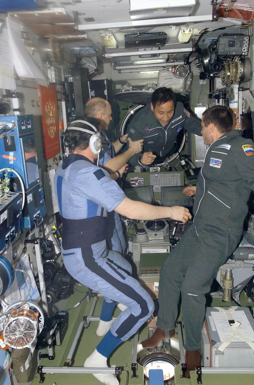 ISS006-E-50604 (28 April 2003) --- Astronaut Edward T. Lu, Expedition 7 NASA ISS science officer and flight engineer, floats into the Zvezda Service Module on the International Space Station (ISS), assisted by astronaut Kenneth D. Bowersox, Expedition 6 mission commander. Also pictured are cosmonauts Nikolai M. Budarin (left foreground), Expedition 6 flight engineer, and Yuri I. Malenchenko, Expedition 7 mission commander. Astronaut Donald R. Pettit (out of view), Expedition 6 NASA ISS science officer, photographed this image. Budarin and Malenchenko represent Rosaviakosmos.