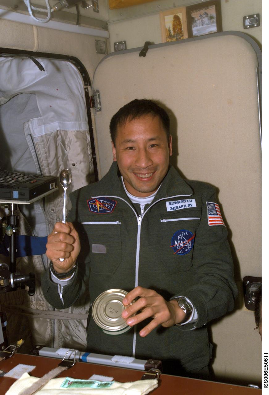 ISS006-E-50611 (28 April 2003) --- Astronaut Edward T. Lu, Expedition Seven NASA ISS science officer and flight engineer, prepares to eat a meal in the Zvezda Service Module on the International Space Station (ISS).