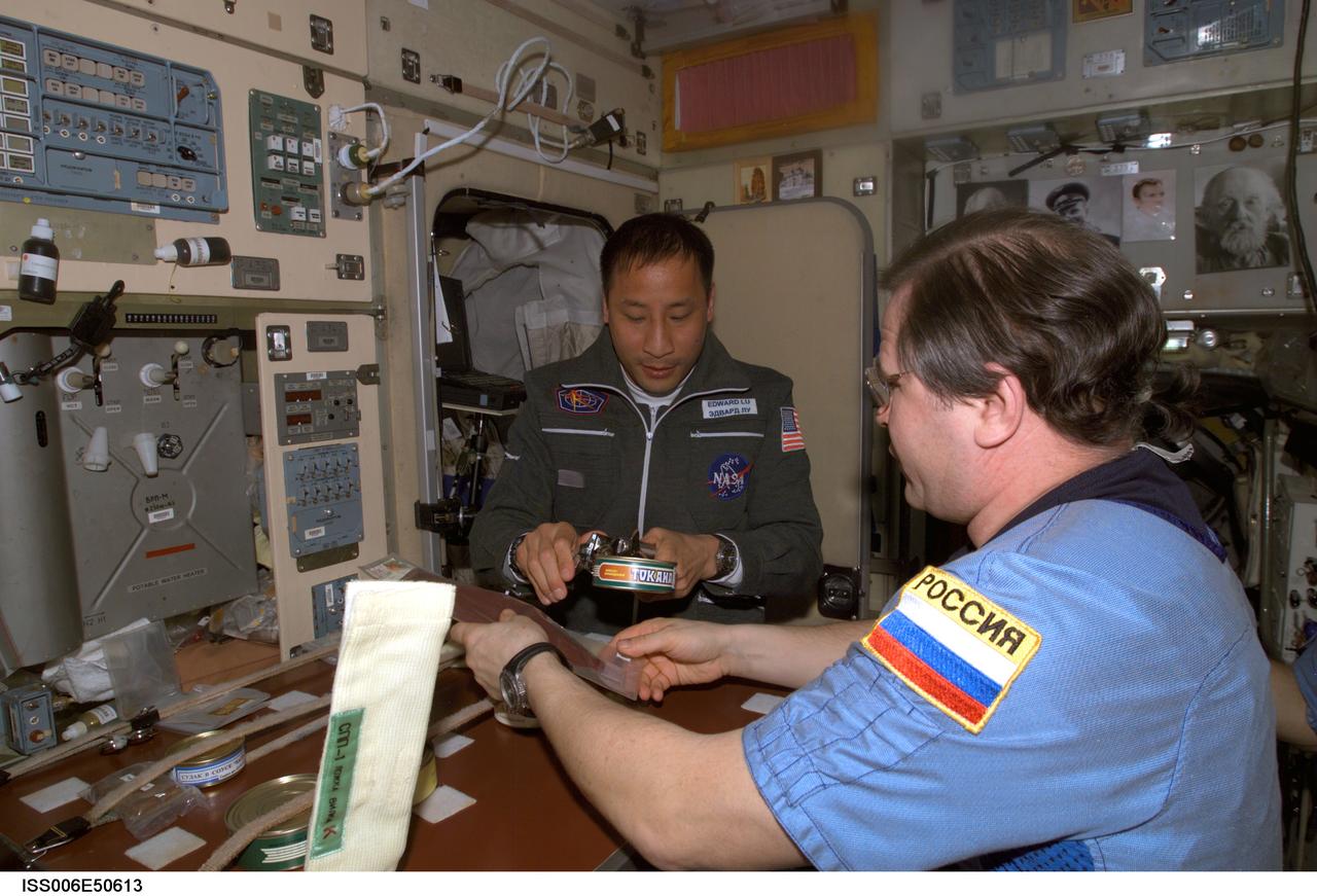 ISS006-E-50613 (28 April 2003) --- Cosmonaut Nikolai M. Budarin (foreground), Expedition Six flight engineer, and astronaut Edward T. Lu, Expedition Seven NASA ISS science officer and flight engineer, share a meal in the Zvezda Service Module on the International Space Station (ISS). Budarin represents Rosaviakosmos.