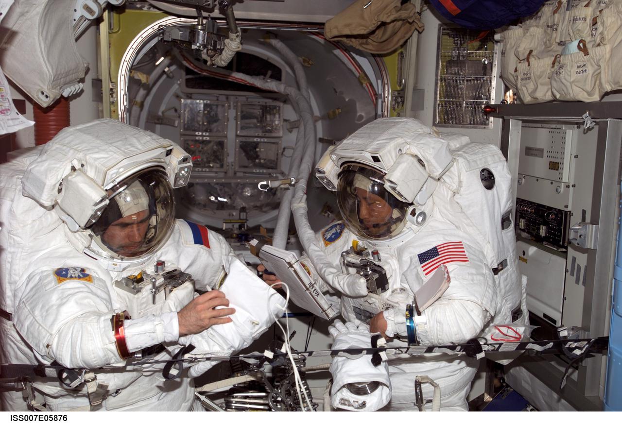 ISS007-E-05876 (28 May 2003) --- Cosmonaut Yuri I. Malenchenko (left), Expedition Seven mission commander, and astronaut Edward T. Lu, NASA ISS science officer and flight engineer, perform an Extravehicular Mobility Unit (EMU) spacesuit fit check and don/doff dry-run in the Quest airlock on the International Space Station (ISS). The objective was to check out the equipment and provide the crew with training for preparing for a two-person spacewalk without intravehicular (IV) crewmember support, should it become necessary. Malenchenko represents Rosaviakosmos.