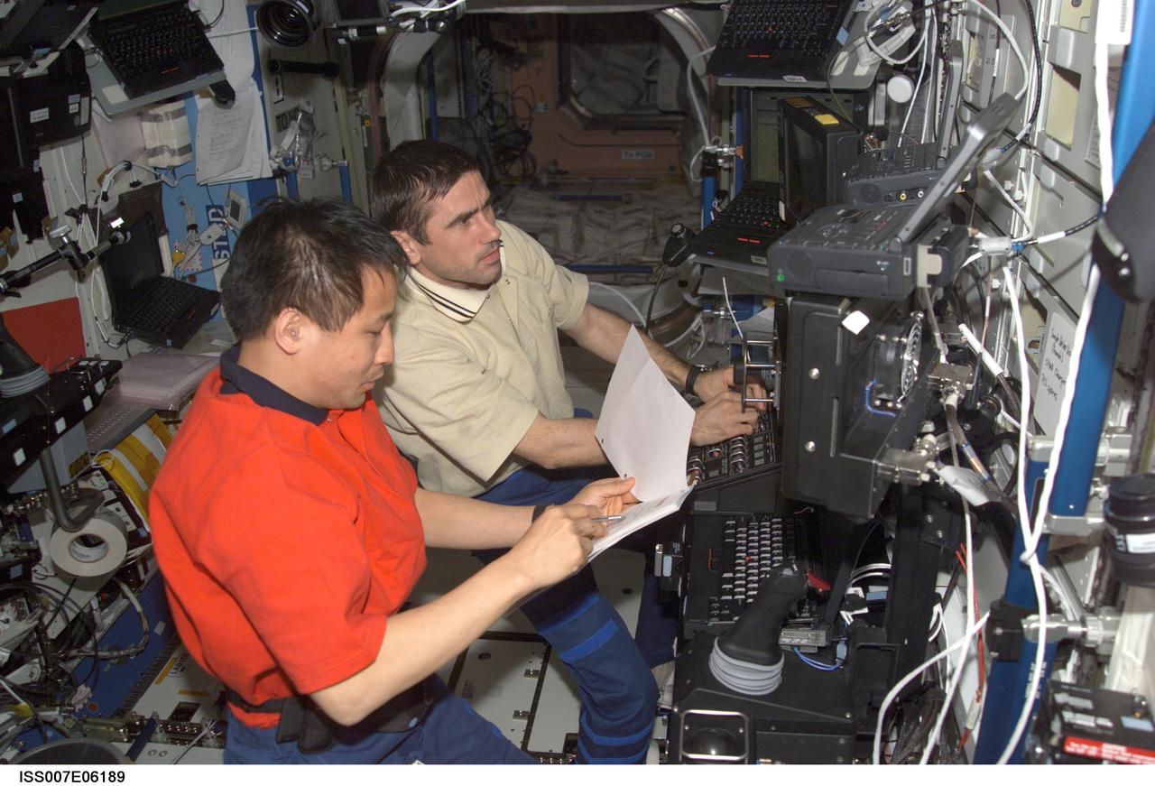 ISS007-E-06189 (4 June 2003) --- Astronaut Edward T. Lu (foreground), Expedition 7 NASA ISS science officer and flight engineer, and cosmonaut Yuri I. Malenchenko, mission commander, work the controls of the Canadarm2 from inside the Destiny laboratory on the International Space Station (ISS). Malenchenko represents Rosaviakosmos.