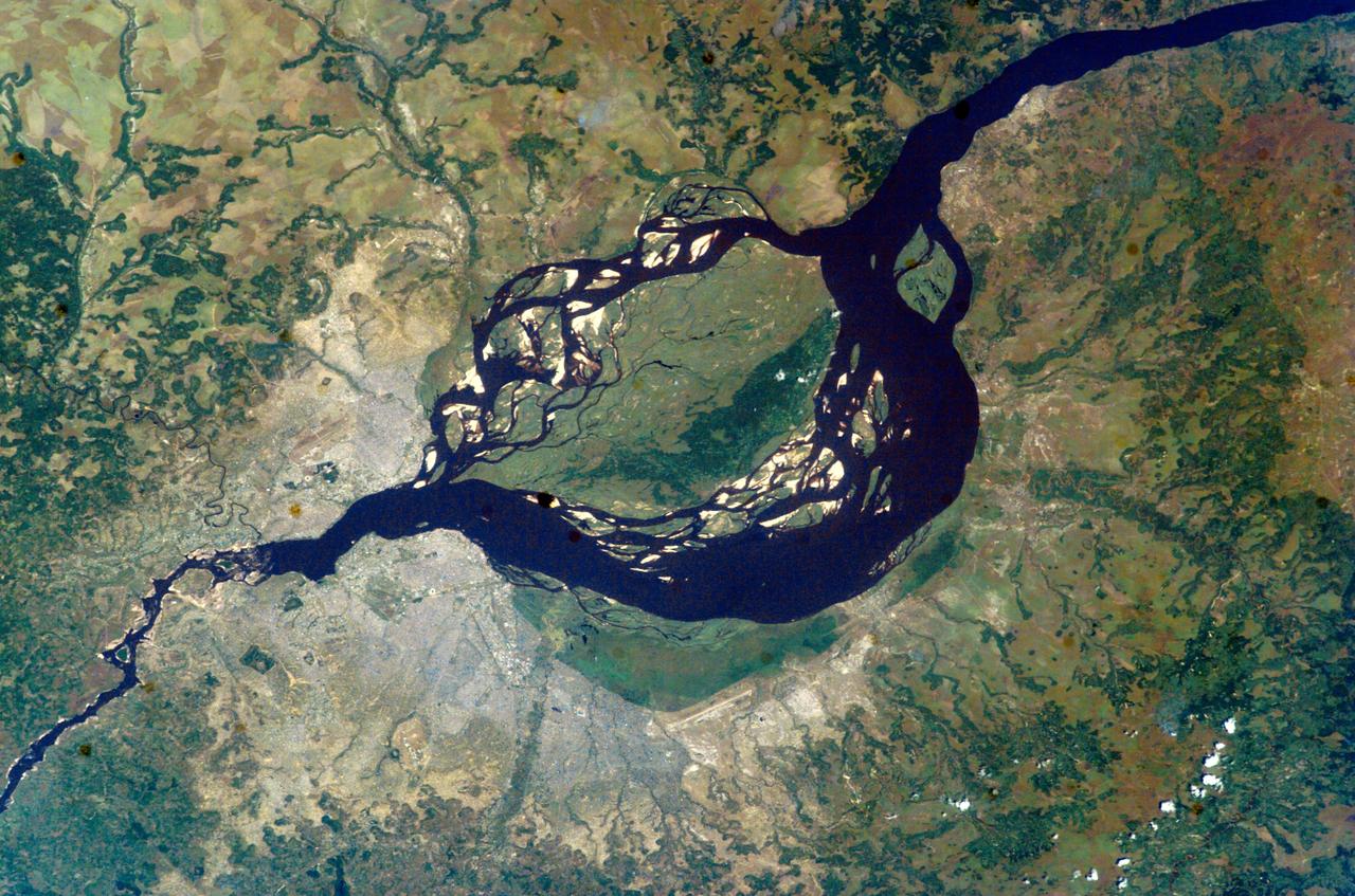ISS007-E-06305 (6 June 2003) --- This image featuring two capital cities on opposite banks of the Congo River was taken by an Expedition 7 crewmember onboard the International Space Station (ISS). The smaller city is Brazzaville on the north side of the river, and Kinshasa on the south side. The cities lie at the downstream end of an almost circular widening in the river known as Stanley Pool. The international boundary follows the south shore of the pool (~30 kilometers in diameter). The Congo River exits the pool through a markedly narrowed channel at a series of whitewater rapids that can be seen in this view from space.