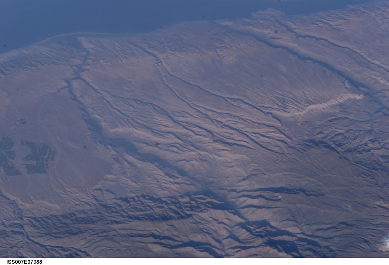 ISS007-E-07388 (14 June 2003) --- Some of the deepest canyons in the world cut west to the Pacific from the high crest of the Andes Mountains in Peru. This view taken by an Expedition 7 crewmember onboard the International Space Station (ISS) provides a birds-eye view down the canyons of the Rio Camana (center left) and the Rio Ocona (upper right). The low early morning sun highlights the extreme topography created by rapidly uplifting mountains and powerful water erosion by water dropping nearly 10,000 feet in this view. At the edge of the image are the snowy flanks of Nevado Coropuna, the highest mountain in the Cordillera Occidental (6613 meters). The coastal city of Camana is visible in the upper left.