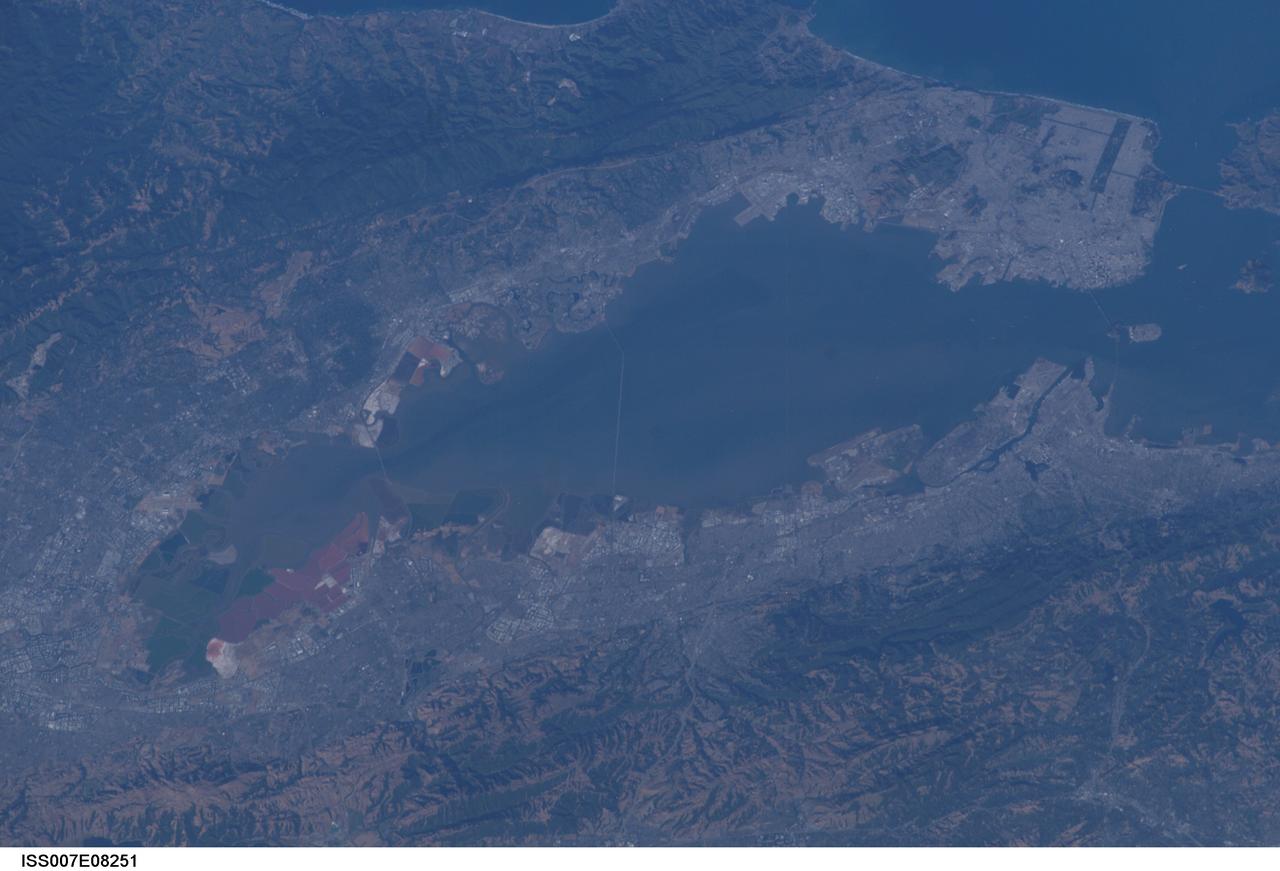 ISS007-E-08251 (25 June 2003) --- This photo featuring the San Francisco Bay area in California was photographed from the International Space Station (ISS) by astronaut Edward T. Lu, Expedition 7 NASA ISS science officer and flight engineer. The San Francisco Bay Bridge, Alcatraz Island, Golden Gate Bridge, and Golden Gate Park are visible at upper right. Stanford University and red salt ponds on the bay near Fremont at lower left.