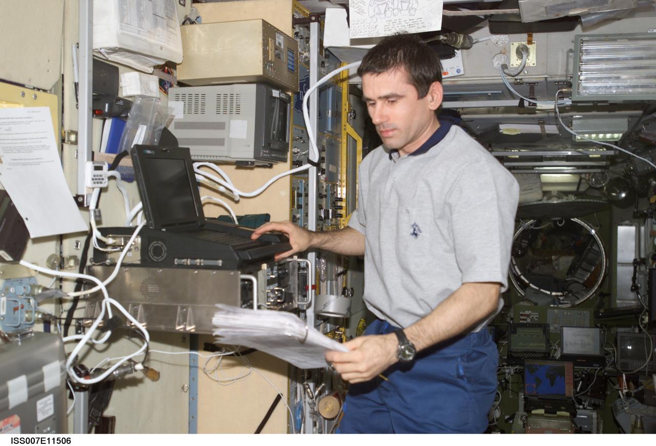 ISS007-E-11506 (31 July 2003) --- Cosmonaut Yuri I. Malenchenko, Expedition 7 mission commander, uses a computer as he reads a procedures checklist in the Zvezda Service Module on the International Space Station (ISS). Malenchenko represents Rosaviakosmos.