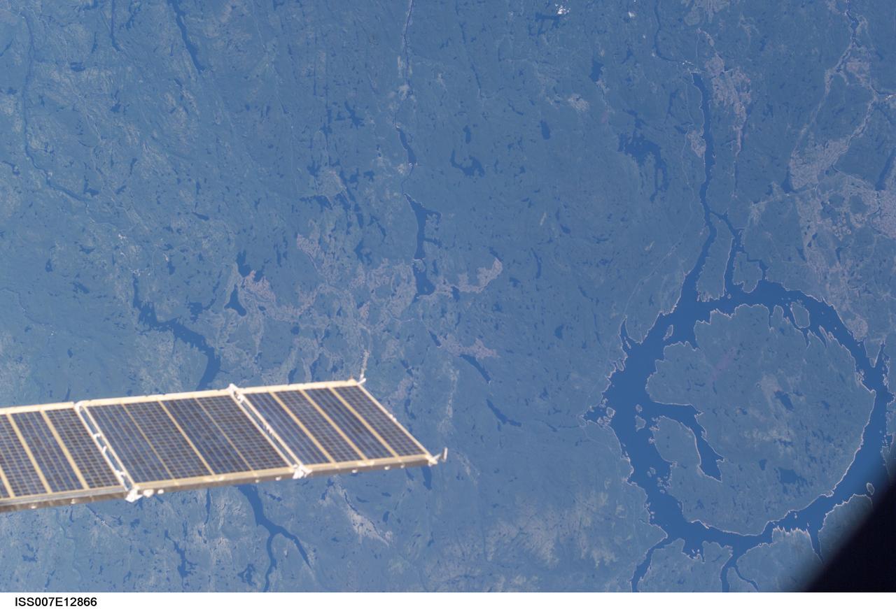 ISS007-E-12866 (17 August 2003) --- This photo showing the Manicouagan Reservoir in Quebec, Canada, and a partial view of a solar array panel was taken by an Expedition 7 crewmember onboard the International Space Station (ISS).
