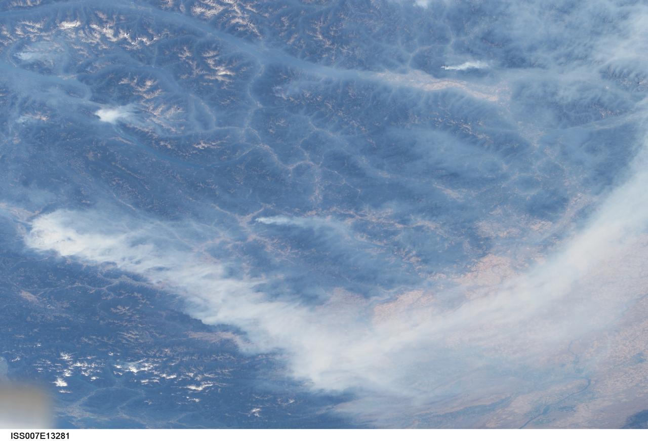 ISS007-E-13281 (20 August 2003) --- This view features forest fires in the Canadian province of British Columbia where some 620,000 acres of forest were consumed in almost 2,500 fires. Here the Rocky Mountains have both lofty, snow-capped peaks and long, narrow valleys that create special conditions and problems with air quality from these smoky fires. This image taken by one of the Expedition 7 crewmembers onboard the International Space Station (ISS) illustrates how smoke has become trapped in valleys where light winds and cold air drainage from the higher elevations have created temperature inversions. Note how the snowy peaks of the mountains are relatively smoke-free while the long, north-south valleys of Kootenay Lake and Columbia River are filled with trapped aerosols from the plumes of the large fires situated in the southwest. Meanwhile shifting winds have now swept the bulk of the plumes southeastward over the Columbia River Basin of Washington.