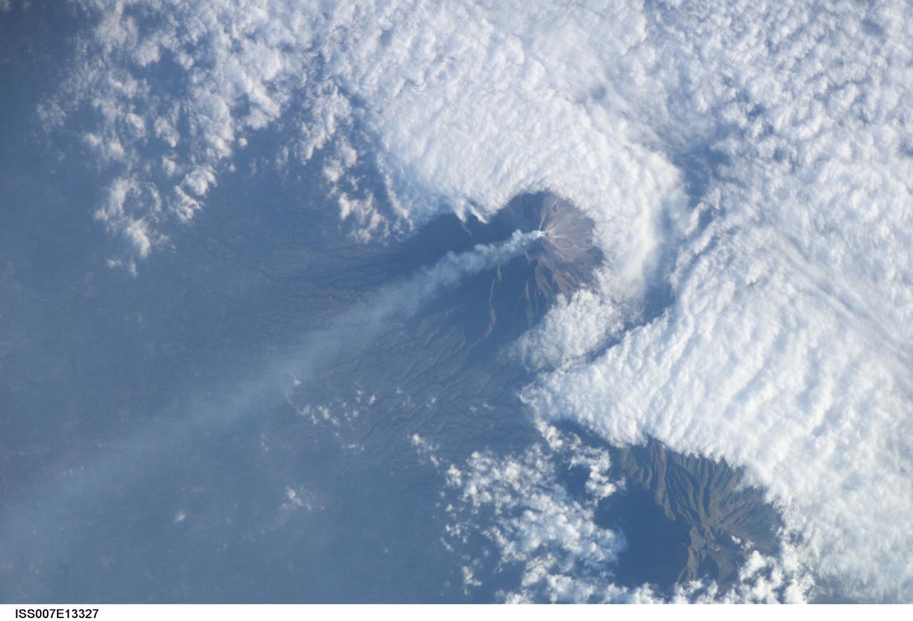 ISS007-E-13327 (24 August 2003) --- This view featuring Java&#0146;s Merapi volcano was photographed by one of the Expedition 7 crewmembers onboard the International Space Station (ISS). At 2,911 meters, the summit of Merapi and its vigorous steam plume rises above a bank of stratus clouds. One of Indonesia&#0146;s most active volcanoes, it has been almost continuously active for nearly ten years, including periodic pyroclastic flows and avalanches.  The volcano is located less than 25 miles north of the city of Yogykarta in central Java.