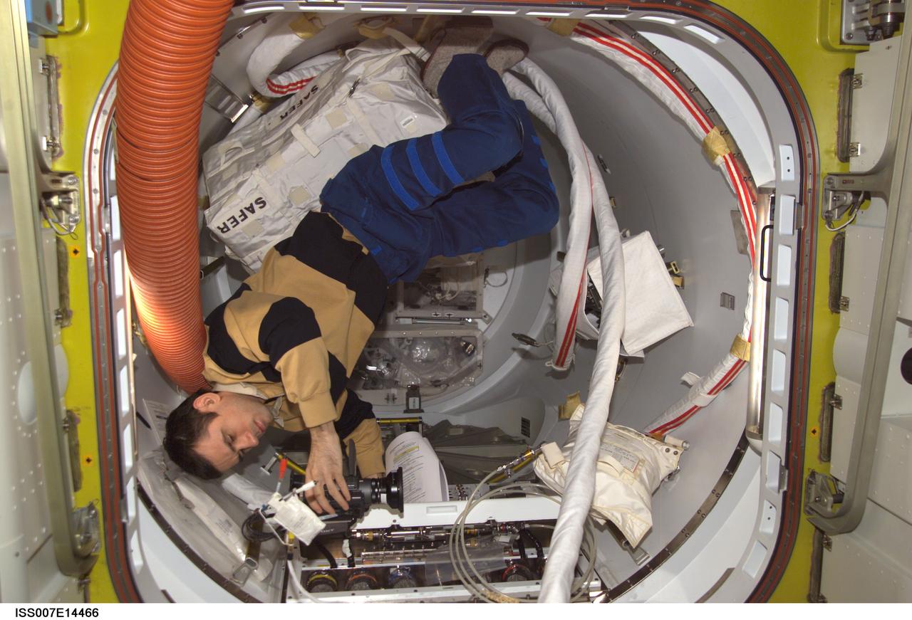 ISS007-E-14466 (5 September 2003) --- Cosmonaut Yuri I. Malenchenko, Expedition 7 mission commander, sets up a video camera to document a review of one of the Extravehicular Mobility Unit (EMU) space suits in the Quest airlock on the International Space Station (ISS). Malenchenko represents Rosaviakosmos.