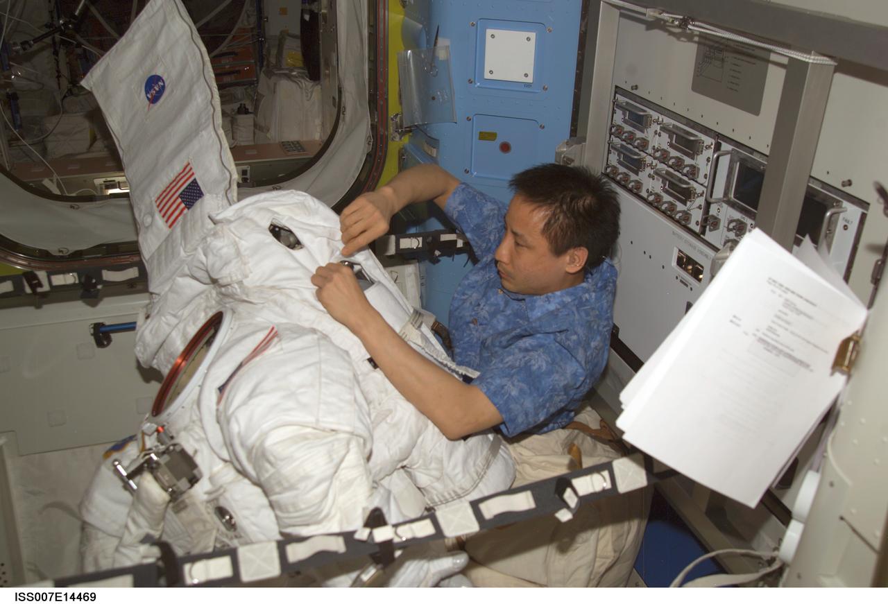 ISS007-E-14469 (5 September 2003) --- Astronaut Edward T. Lu, Expedition 7 NASA ISS science officer and flight engineer, performs routine maintenance on an Extravehicular Mobility Unit (EMU) space suit in the Quest airlock on the International Space Station (ISS). The work represents a mid-term checkout and included emptying and refilling the suit&#0146;s water tank and loops, cycling relief valves, checking sensors and collecting data, a leak check and running the suit&#0146;s fan for two hours to lubricate it.