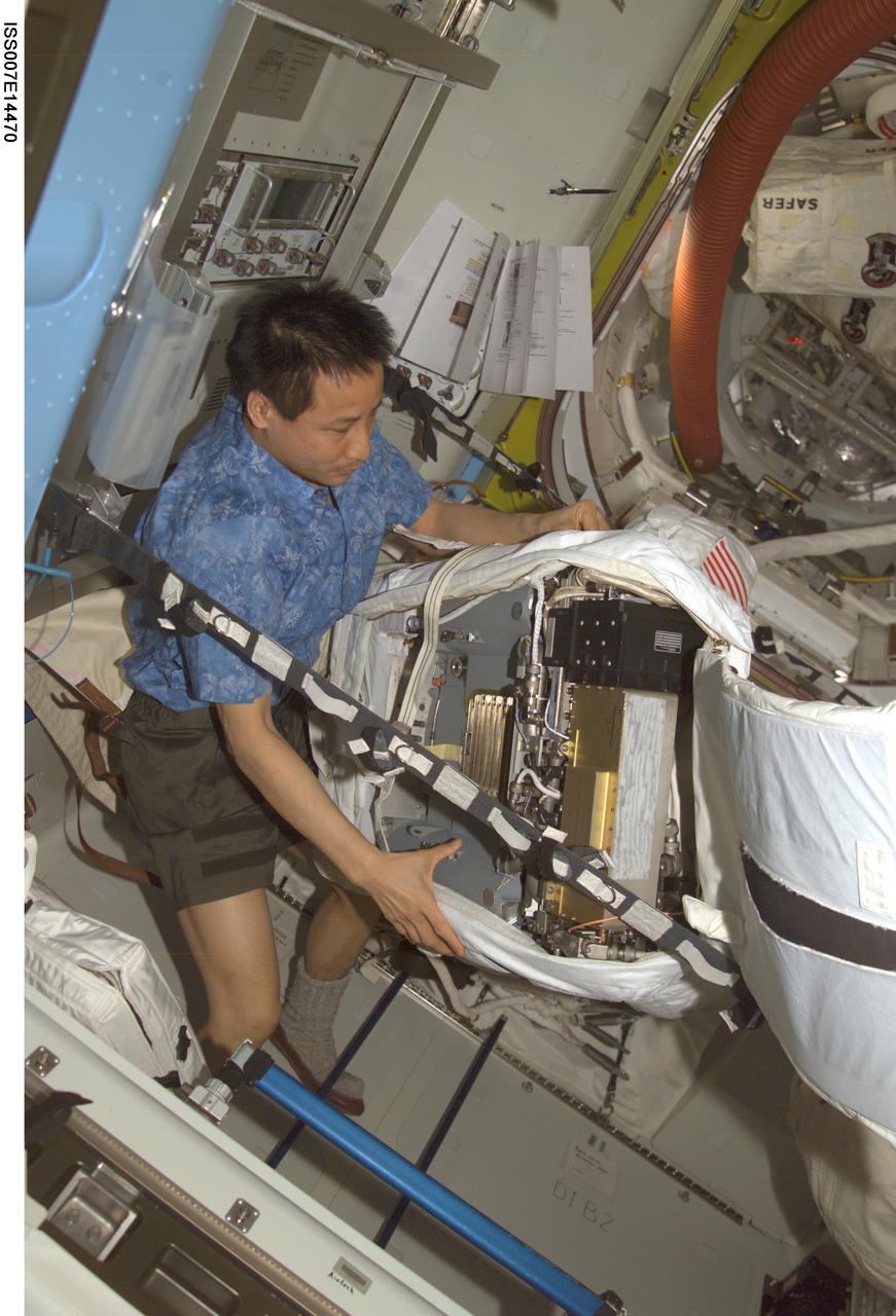 ISS007-E-14470 (5 September 2003) --- Astronaut Edward T. Lu, Expedition 7 NASA ISS science officer and flight engineer, performs routine maintenance on an Extravehicular Mobility Unit (EMU) space suit in the Quest airlock on the International Space Station (ISS). The work represents a mid-term checkout and included emptying and refilling the suit&#0146;s water tank and loops, cycling relief valves, checking sensors and collecting data, a leak check and running the suit&#0146;s fan for two hours to lubricate it.