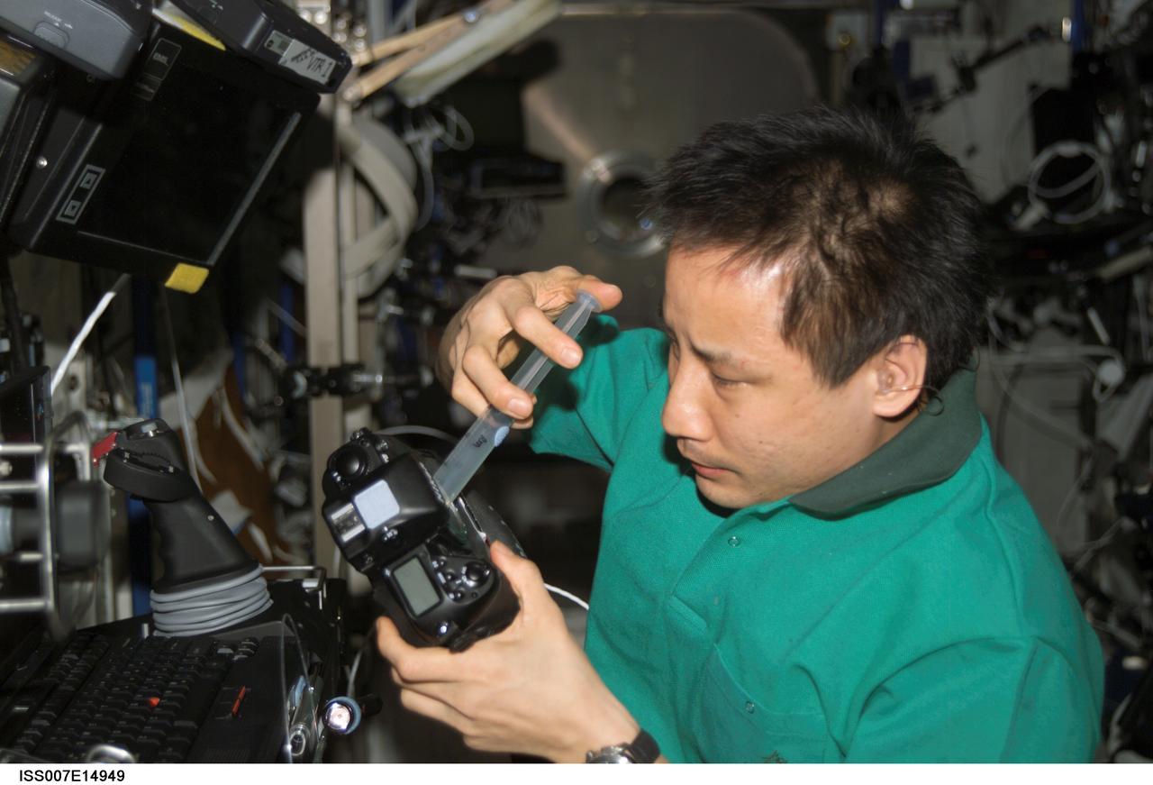 ISS007-E-14949 (16 September 2003) --- Astronaut Edward T. Lu, Expedition 7 NASA ISS science officer and flight engineer, cleans the dust off the charged couple device (CCD) on a digital still camera in the Destiny laboratory on the International Space Station (ISS).