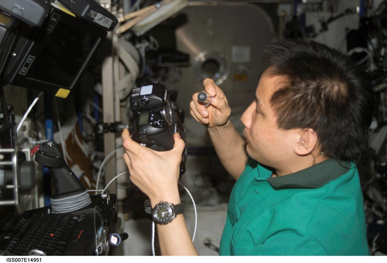 ISS007-E-14951 (16 September 2003) --- Astronaut Edward T. Lu, Expedition 7 NASA ISS science officer and flight engineer, cleans the dust off the charged couple device (CCD) on a digital still camera in the Destiny laboratory on the International Space Station (ISS).