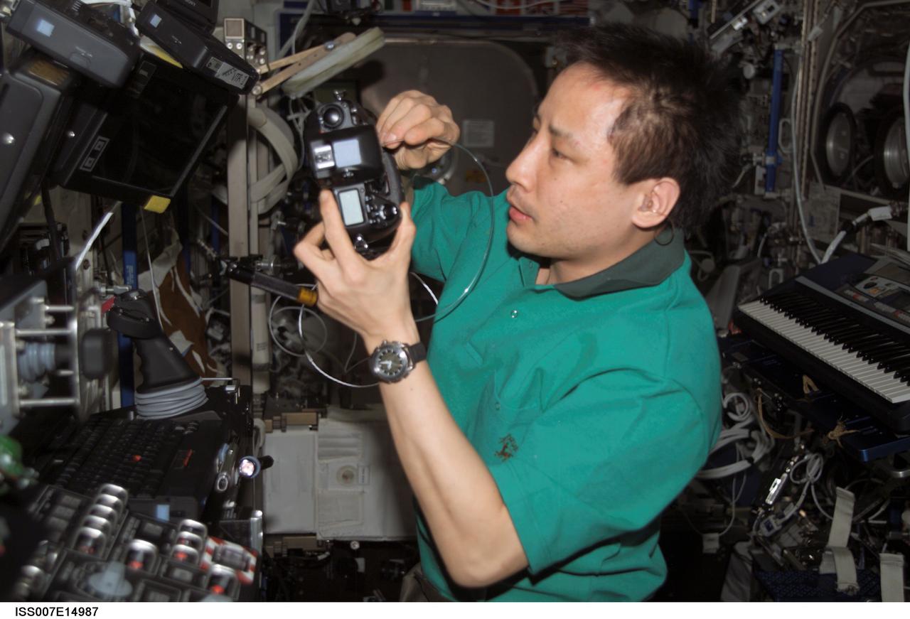 ISS007-E-14987 (16 September 2003) --- Astronaut Edward T. Lu, Expedition 7 NASA ISS science officer and flight engineer, cleans the dust off the charged couple device (CCD) on a digital still camera in the Destiny laboratory on the International Space Station (ISS).