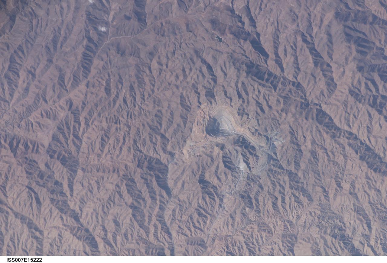 ISS007-E-15222 (22 September 2003) --- This view in southern Peru, photographed by an Expedition 7 crewmember onboard the International Space Station (ISS), features the Toquepala copper mine, a steep sided and stepped open-pit mine. Mid-afternoon sunlight of the arid slopes of the central Andes Mountains provides an accent to the mine contours. At the surface the open pit is 6.5 kilometers across and it descends more than 3000 meters into the earth. A dark line on the wall of the pit is the main access road to the bottom.