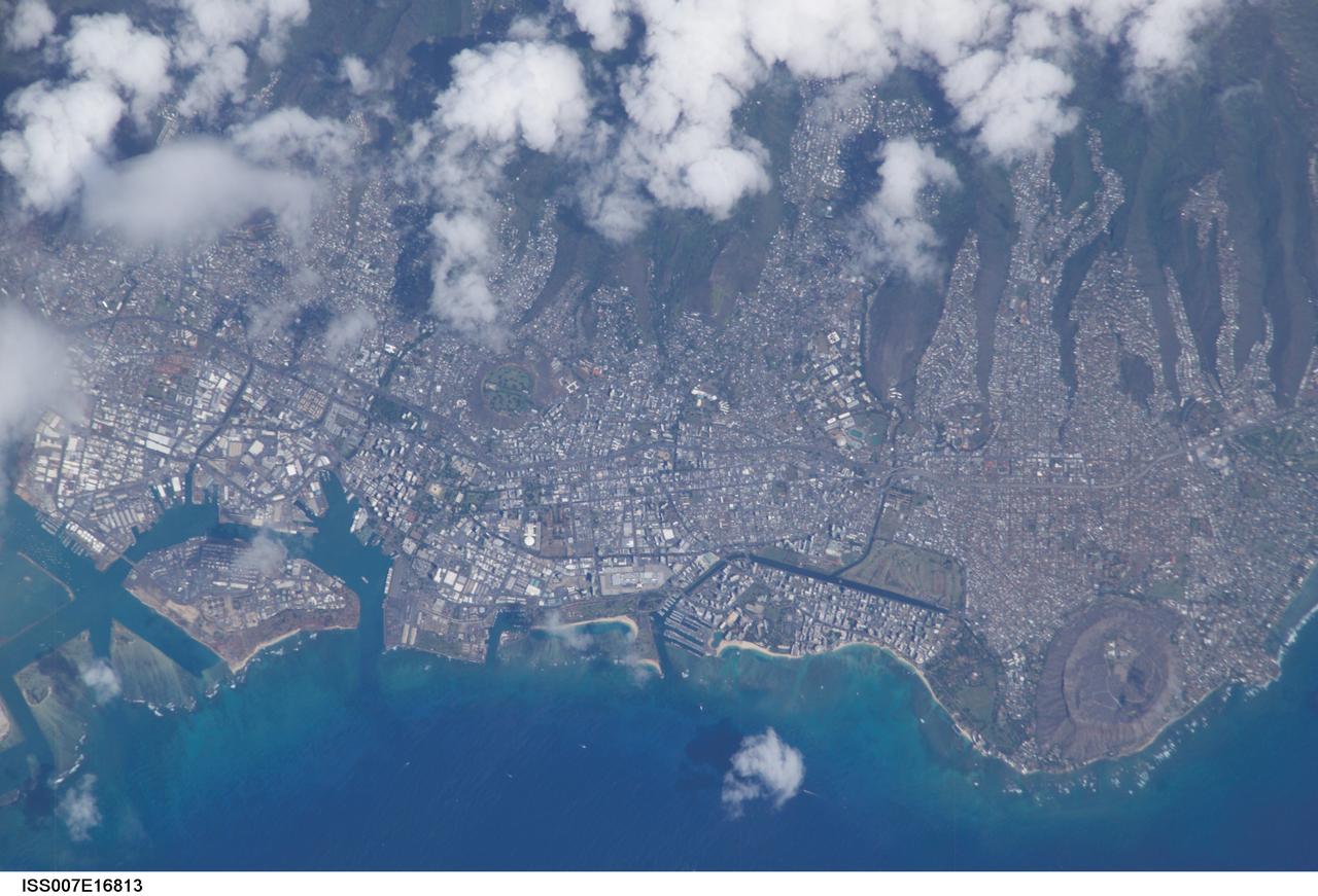 ISS007-E-16813 (8 October 2003) --- This view featuring Honolulu, Hawaii was photographed by an Expedition 7 crewmember onboard the International Space Station (ISS). The city is striking for the way it is bound by surrounding geography. Built-up fingers of the city extend northeast onto the steep volcanic slopes and surround the volcanic craters of Punchbowl crater and Diamond Head, leaving undeveloped only parklands and the steepest ridges. They are both tuff cones that formed as magma from the erupting volcano came in contact with ground water at a time when sea levels were higher than they are now. As the water turned to steam, according to NASA scientists, it caused an explosion that formed a hill of ash with a broad crater in the center.