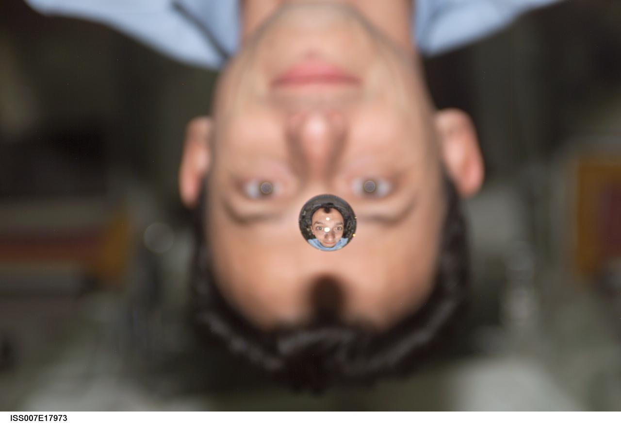 ISS007-E-17973 (25 October 2003) --- European Space Agency (ESA) astronaut Pedro Duque of Spain watches a water bubble float between him and the camera, showing his image refracted, on the International Space Station (ISS).