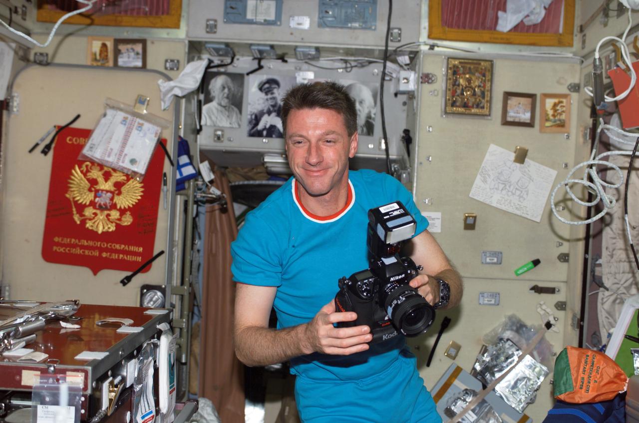 ISS007-E-17982 (25 Oct. 2003) --- Astronaut C. Michael Foale, Expedition 8 mission commander and NASA ISS science officer, holds a camera in the Zvezda Service Module on the International Space Station (ISS).