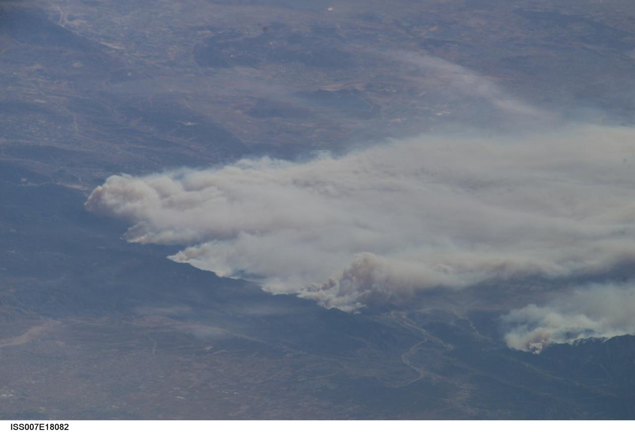 ISS007-E-18082 (26 October 2003) --- The fires in the San Bernardino Mountains, fueled by Santa Ana winds, burned out of control on the  morning of Oct. 26, 2003, when these images were taken from the International Space Station at roughly 11 a.m. (PST). Thick yellow smoke blows south, blanketing the valley below. This image and ISS007-E-18078, looking southeast, capture the smoke pall as the ISS approached and passed over the region. Image numbers 18078 and 18082 were taken roughly a minute apart. A small break in the smoke marks Cajon pass. Content was provided by JSC&#0146;s Earth Observation Lab. The International Space Station Program {link to http://spaceflight.nasa.gov} supports the laboratory to help crew members take pictures of Earth that will be of the greatest value to scientists and the public, and to make those images freely available on the Internet. Additional images taken by astronauts and cosmonauts can be viewed at the NASA/JSC Gateway to Astronaut Photography of Earth [link to http://eol.jsc.nasa.gov/].