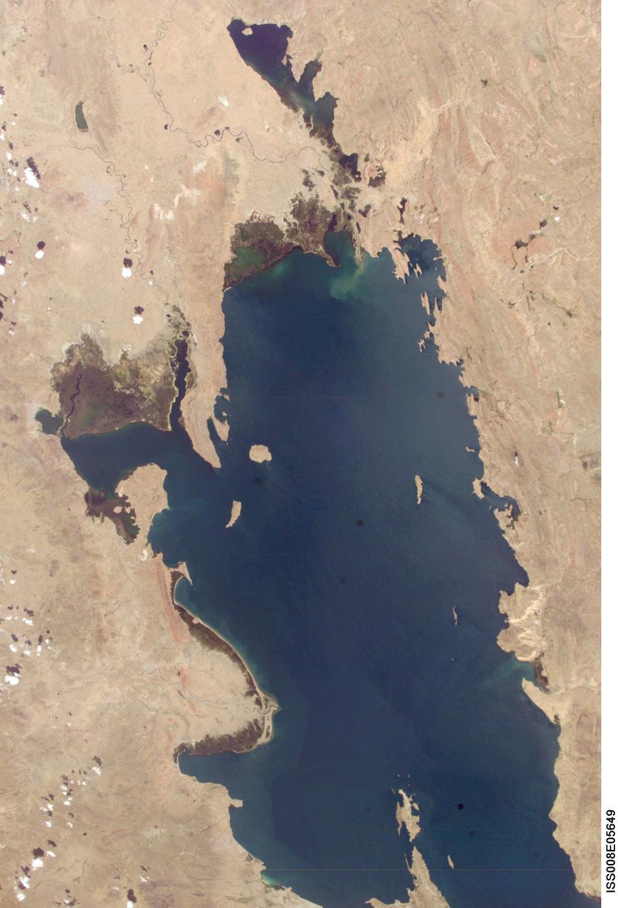 ISS008-E-05649 (8 November 2003) --- Lake Titicaca was featured in this image taken by one of the Expedition 8 crewmembers onboard the International Space Station (ISS). Lake Titicaca, at an elevation of 12,507 feet in the Andean Altiplano, is the highest large lake in the world. More than 120 miles long and 50 miles wide, it was the center of Incan civilization, and today straddles the boundary between Peru and Bolivia. Scientists have studied indicators of the water level changes over time to tease out information about precipitation shifts in the high Andes and the South American tropics. Following are some observations by NASA scientists who are studying this imagery: Because the lake occupies the low point of the Altiplano, much of the water of the high plateau eventually trickles into the lake. And because it is surrounded by mountains, very little of Lake Titicaca&#0146;s water drains out -- the Rio Desguadero is the only major outflow river.  So, like a bathtub with no drain, this large and deep lake (with depths of several hundred feet) has become the collecting basin for thousands of years of sediment. These sediments and their fossils contain clues about past climate conditions. The restricted outflow of the lake creates conditions where even shorter, interannual climate cycles (like El Ni&#0241;o /Southern Oscillation) impact Lake Titicaca&#0146;s water levels. Recent lake level variations have been several meters, with low levels occurring during regional droughts of El Ni&#0241;os. Right now, the region is relatively wet. In this image, the dark greens of the wetlands along the shallower margins of the lake contrast strongly with the surrounding desert. But the even large cities like Puno, Peru (100,000 people) are difficult to discern from the surrounding countryside.