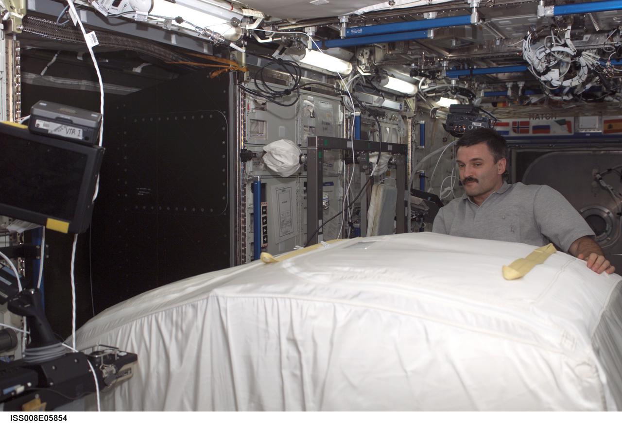 ISS008-E-05854 (12 November 2003) --- Cosmonaut Alexander Y. Kaleri,  Expedition 8 flight engineer, moves a Zero-G Storage Rack (ZSR) in the Destiny laboratory on the International Space Station (ISS). Kaleri, who represents Rosaviakosmos, commanded the Soyuz flight that took the crew to the station last month.
