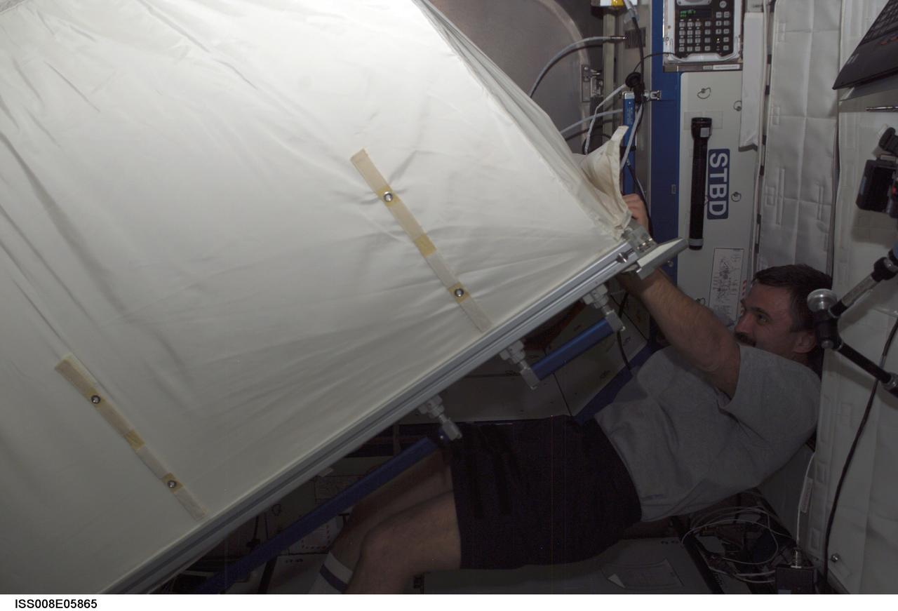 ISS008-E-05865 (12 November 2003) --- Cosmonaut Alexander Y. Kaleri, Expedition 8 flight engineer, moves a Zero-G Storage Rack (ZSR) in the Destiny laboratory on the International Space Station (ISS). Kaleri, who represents Rosaviakosmos, commanded the Soyuz flight that took the crew to the station last month.