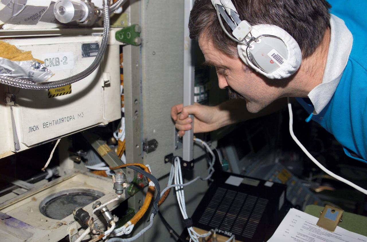 ISS008-E-08615 (16 December 2003) --- Cosmonaut Alexander Y. Kaleri, Expedition 8 flight engineer, works to remove and replace a Heat Exchanger on the SKV-2 Air Conditioner in the Zvezda Service Module on the International Space Station (ISS). Kaleri represents Rosaviakosmos.