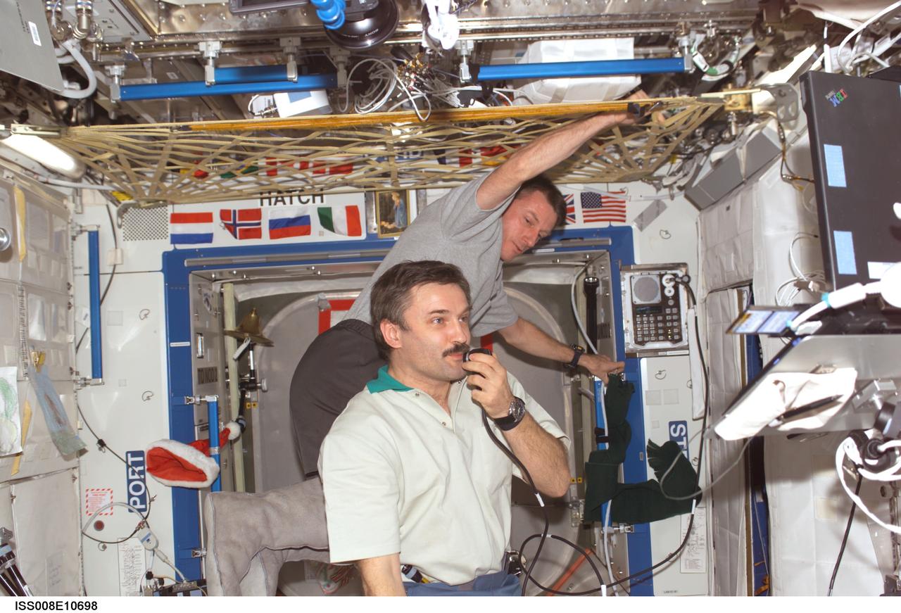 ISS008-E-10698 (28 December 2003) --- Cosmonaut Alexander Y. Kaleri (foreground), Expedition 8 flight engineer, and astronaut C. Michael Foale, mission commander and NASA ISS science officer, conduct a teleconference with the Moscow Support Group for the Russian New Year celebration, via Ku- and S-band, with audio and video relayed to the Mission Control Center (MCC) at Johnson Space Center (JSC). Kaleri represents Rosaviakosmos.